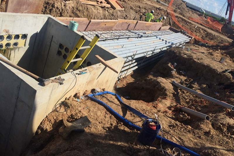 Precast concrete vault set in an excavation with conduit stubbed into the wall