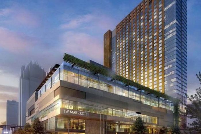 The JW Marriott hotel tower at dusk above its landscaped terrace and lit lobby